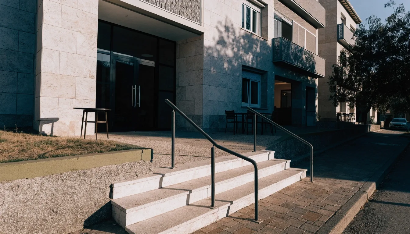 Entrada de un edificio residencial español moderno con la luz rasante de la mañana sobre la fachada de piedra
